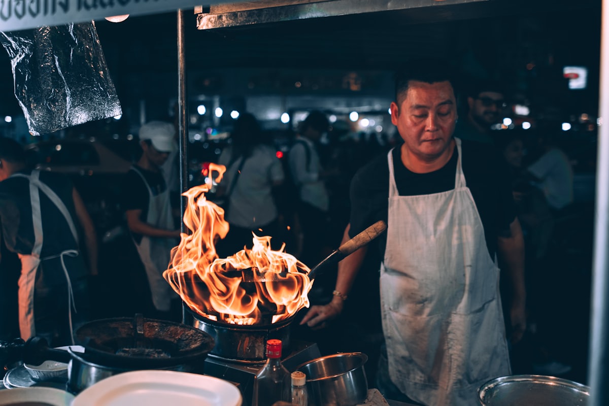 Cook working a wok at a Bangkok street food stall